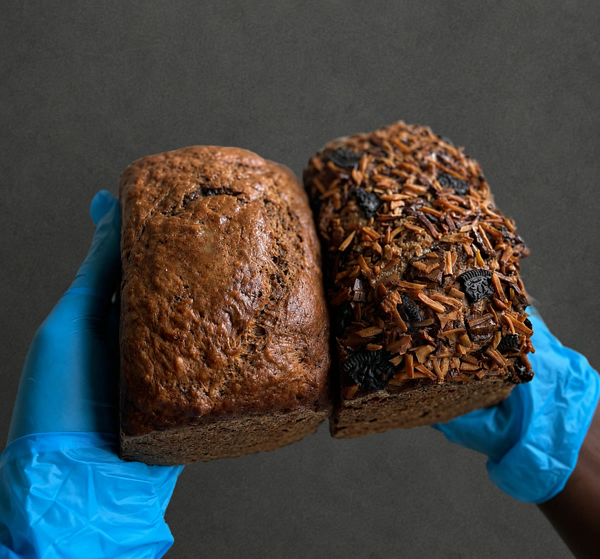 Two loaves of banana bread held in gloved hands
