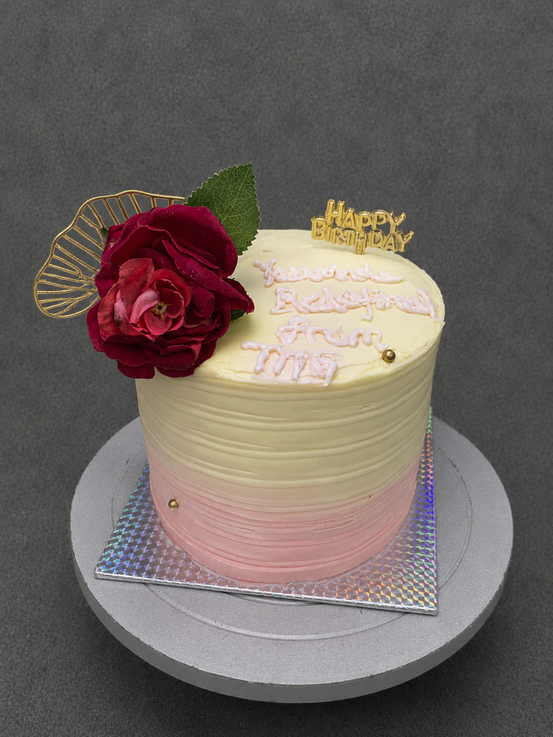 Cream and pink birthday cake with a red rose