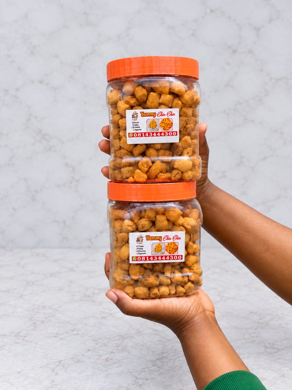 Two jars of chin chin held in hand